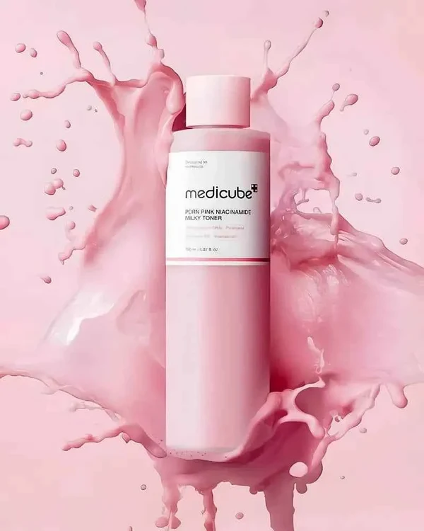 Medicube PDRN Pink Niacinamide Milky Toner bottle surrounded by a realistic pink liquid splash.