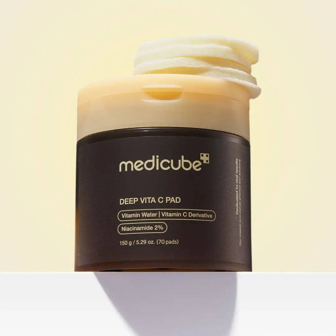 Medicube Deep Vita C Pad jar featuring a dark body, warm yellow lid, and stacked vitamin C infused pads.