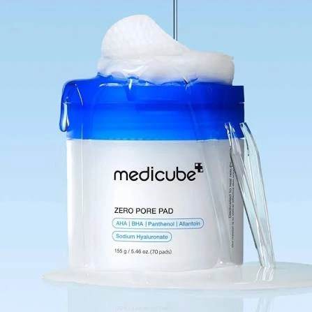 Medicube Zero Pore Pad jar with a vibrant blue cap and saturated exfoliating toner pads stacked on top.